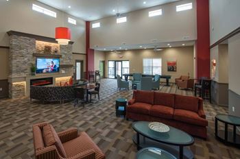 A large room with a stone fireplace and a red couch.